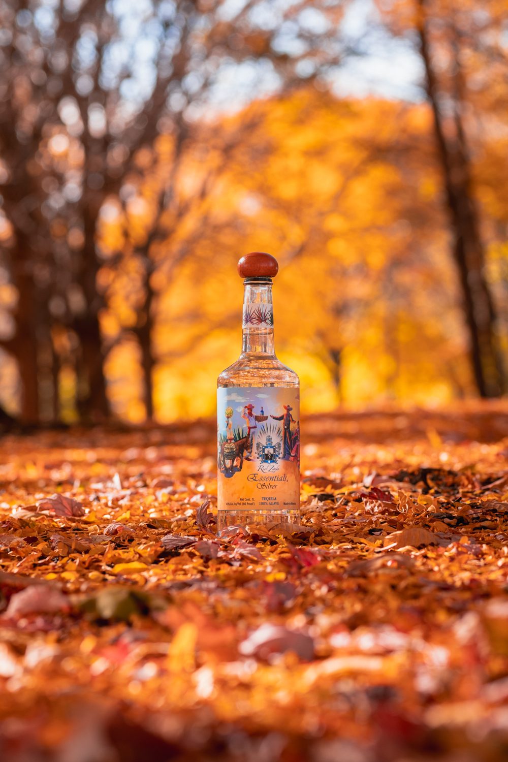A bottle of Real Zepeda Essentials Silver standing on autumn leaves